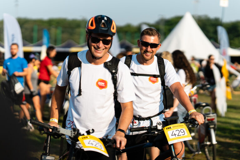 Dwóch uśmiechniętych rowerzystów z numerami startowymi